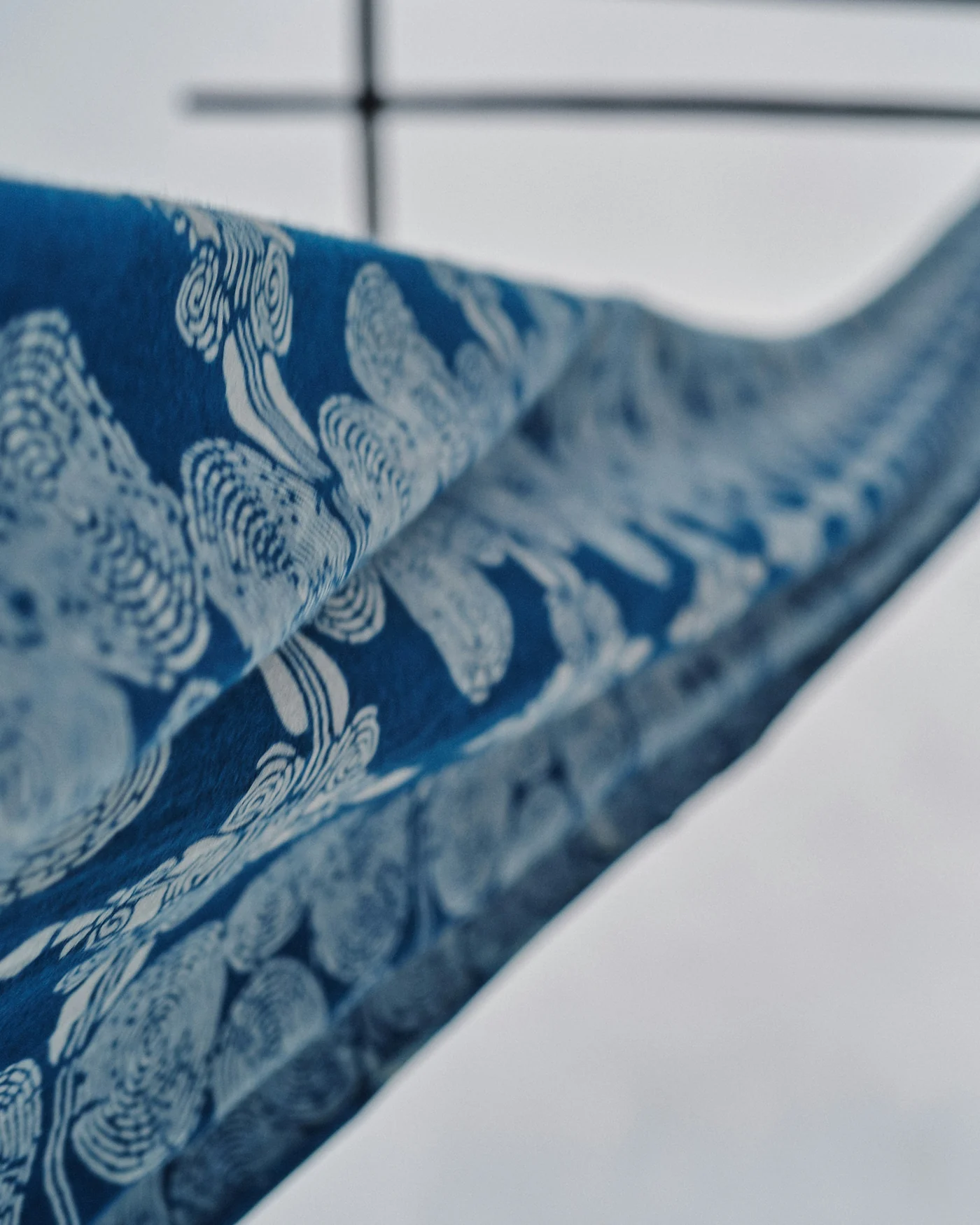 Indigo patterned fabric drying on a wooden frame